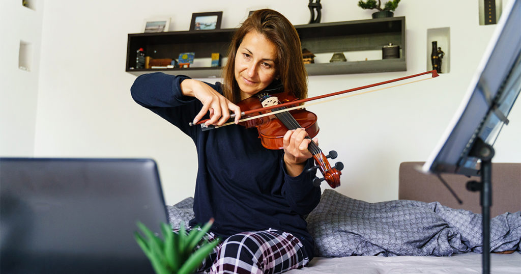 woman playing a violin on her bed
